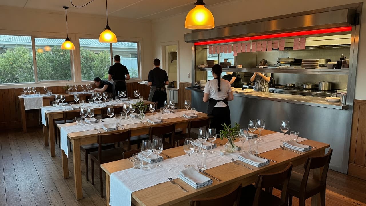 A dining room being set beside an open kitchen pass